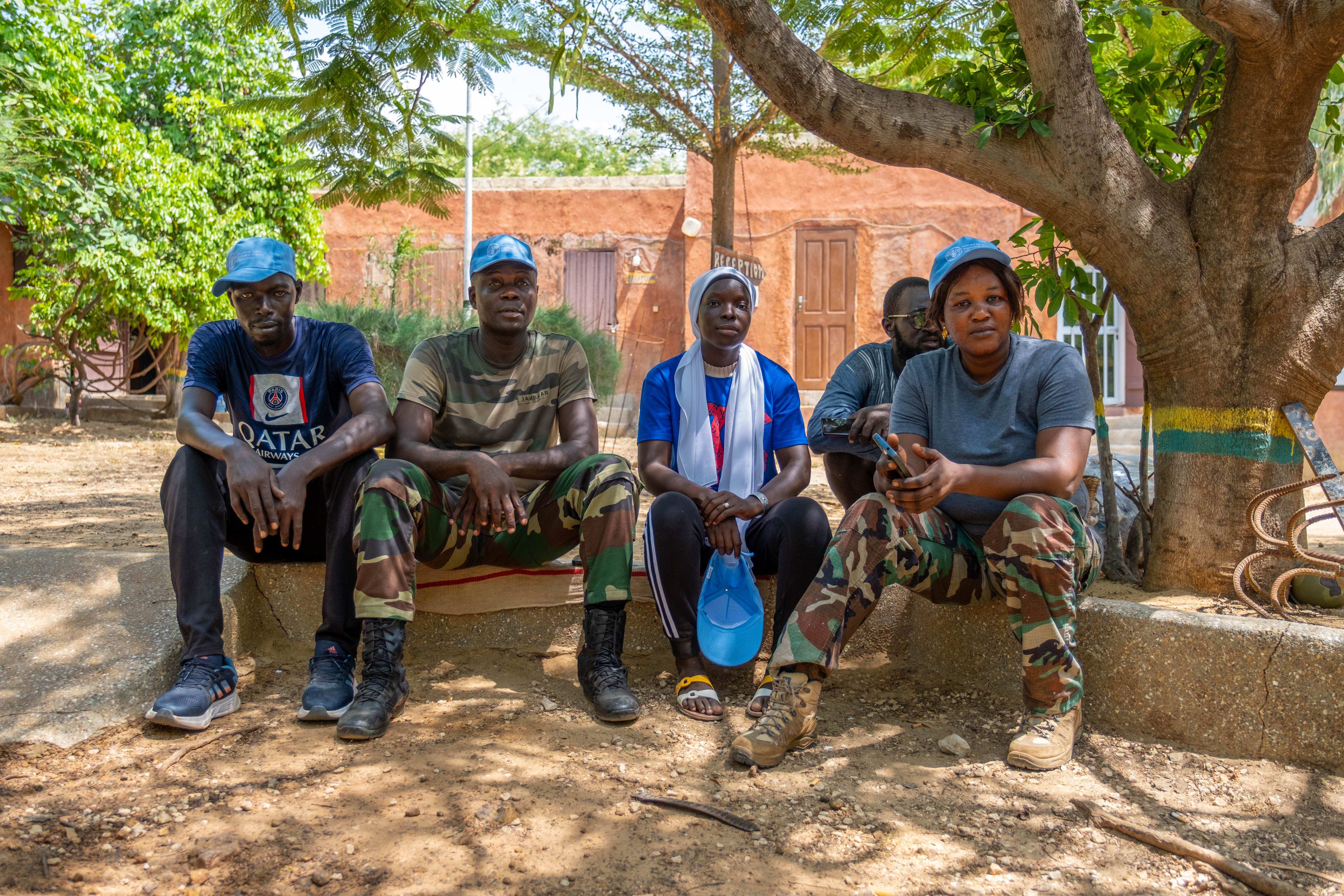 Five workers sitting down under a tree